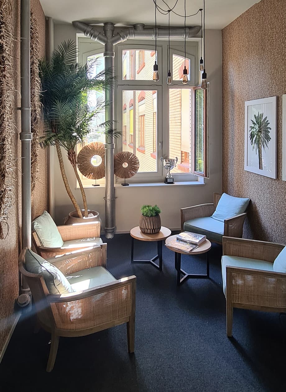 Reading niche with rattan armchairs and a palm at the window