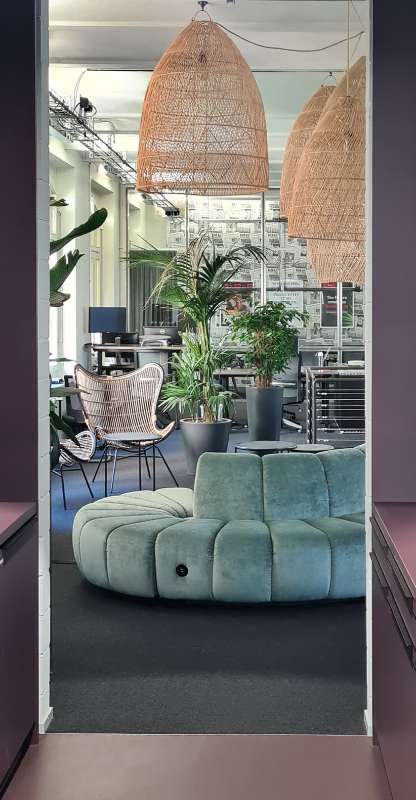 View through a doorway onto the round mint sofa and workspaces