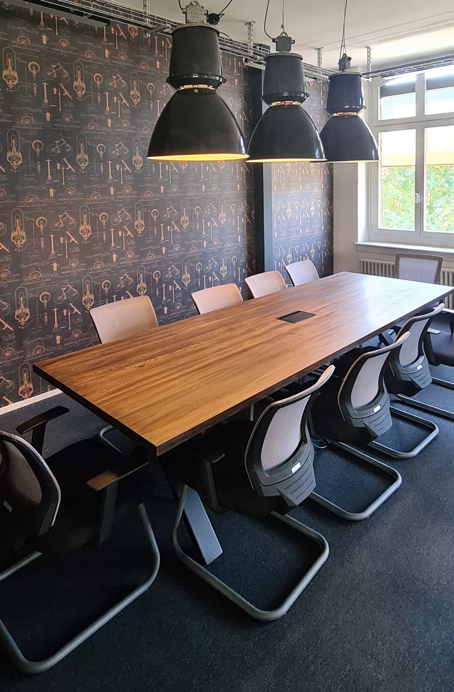 Conference room with long wooden table and industrial pendants