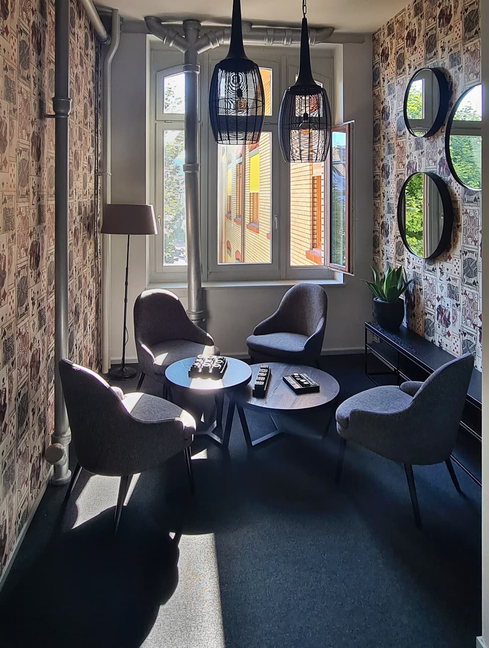 Small lounge with grey armchairs and round mirrors